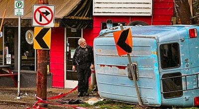 A Central Precinct officer examined the smashed and wedged-in van, while waiting for a second and larger tow truck to arrive to remove it from the sidewalk on Milwaukie Avenue near S.E. Nehalem Street in Sellwood.